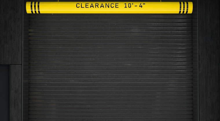 A closed garage door with a yellow sign on it