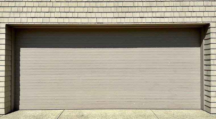 A white fire hydrant in front of a garage door