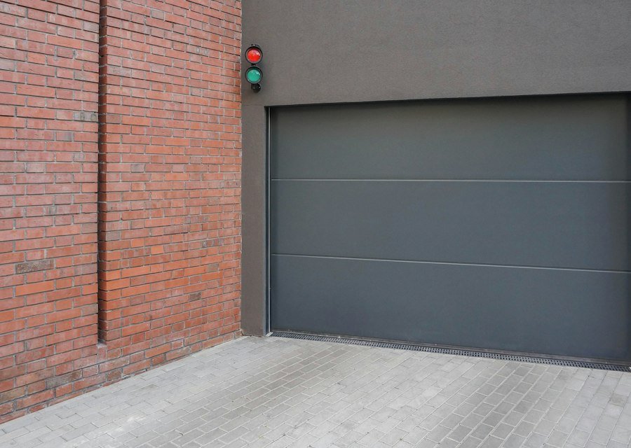 A grey garage door next to a brick wall