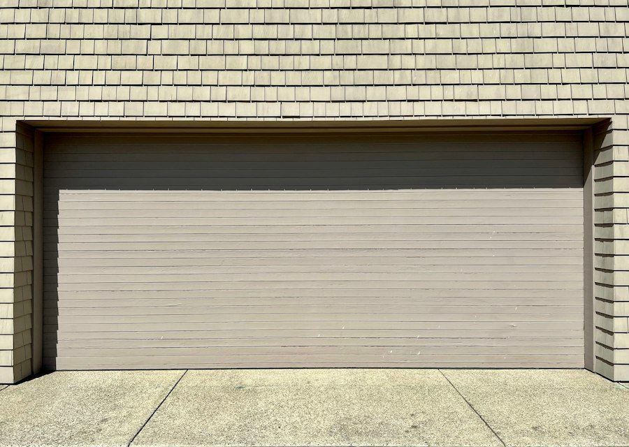 A white fire hydrant in front of a garage door